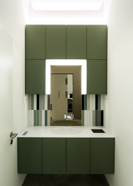 Spiegel und grüner Waschbeckenschrank - Einrichtungsdetail in der Praxis Mitte in Berlin